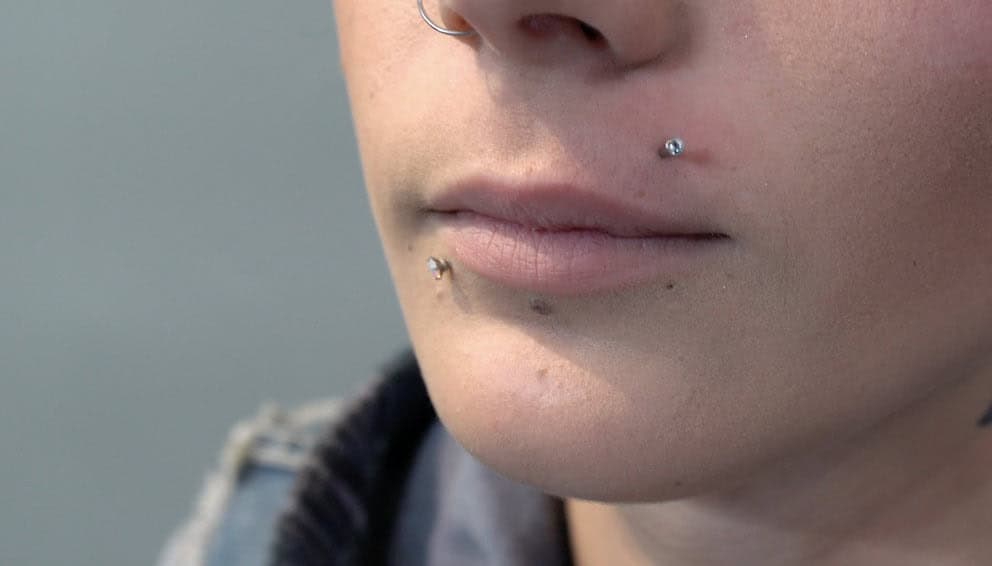 A side profile of someone with a Monroe piercing, showcasing how it enhances their cheekbone structure.